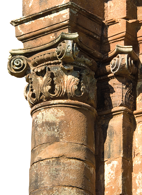 Fotografia. Parte da coluna de uma obra arquitetônica de estilo barroco, com detalhes em alto relevo em destaque.