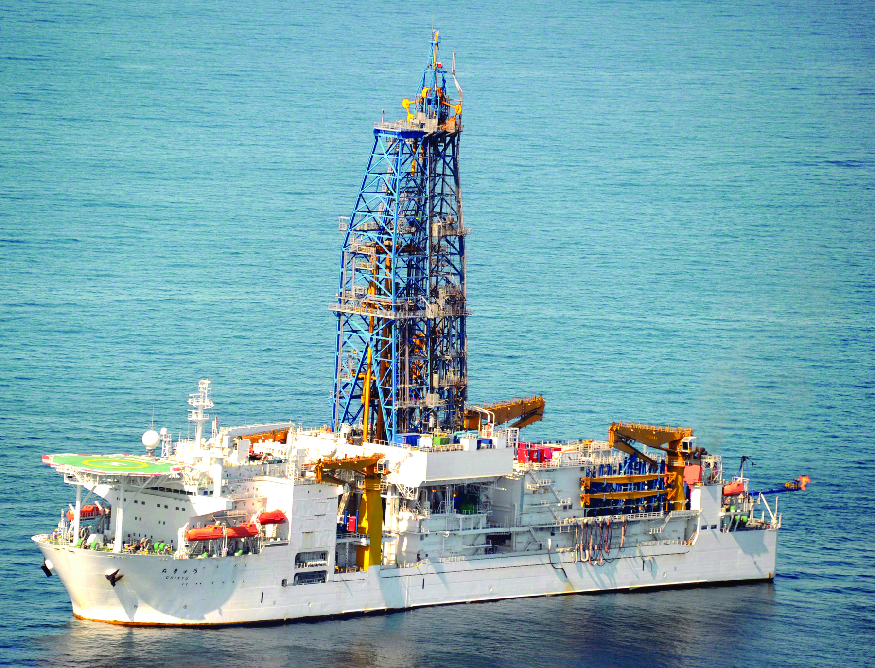 Fotografia de um navio sobre o mar. No centro dele, uma torre de ferro com vários andares.