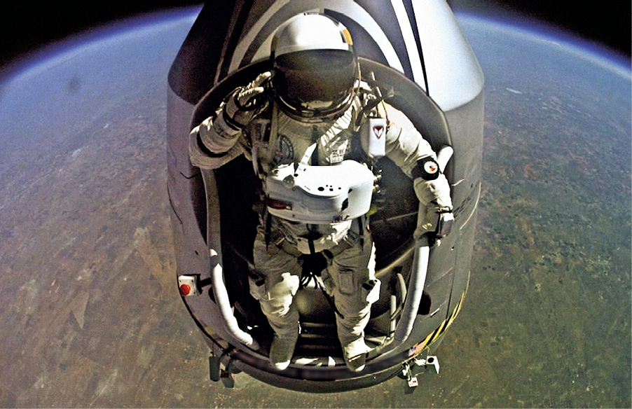 Fotografia de um astronauta dentro de uma cápsula espacial. Ele usa roupa branca e capacete. Ao fundo, o Planeta Terra.