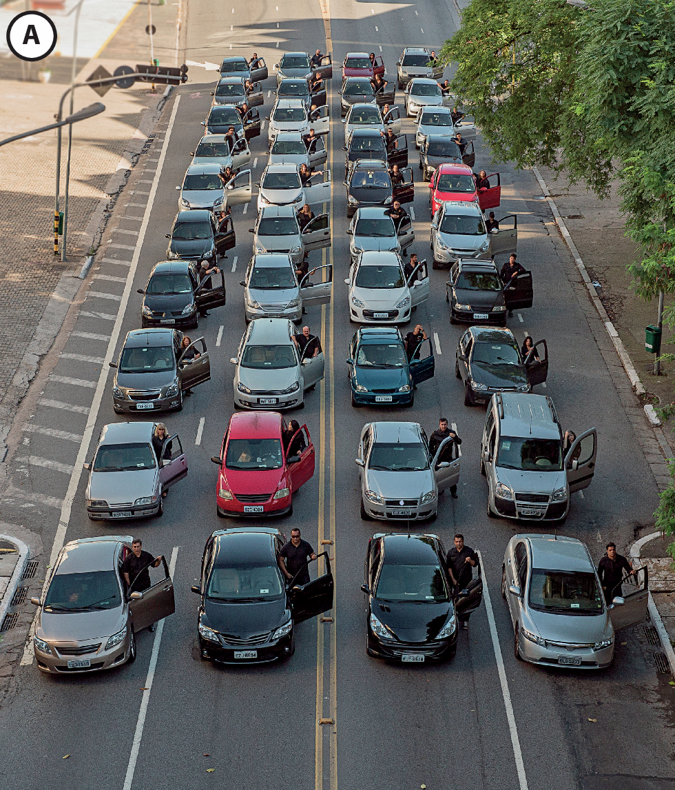 Fotografia A. Rua com quatro fileiras de dez carros cada e uma pessoa ao lado de cada carro.