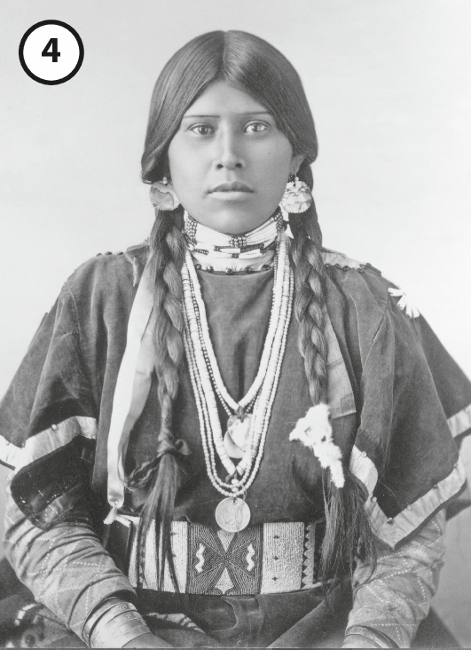 Fotografia em preto e branco 4: Mulher jovem indígena de cabelo longo dividido em duas tranças, vestindo túnica indígena ornamentada.