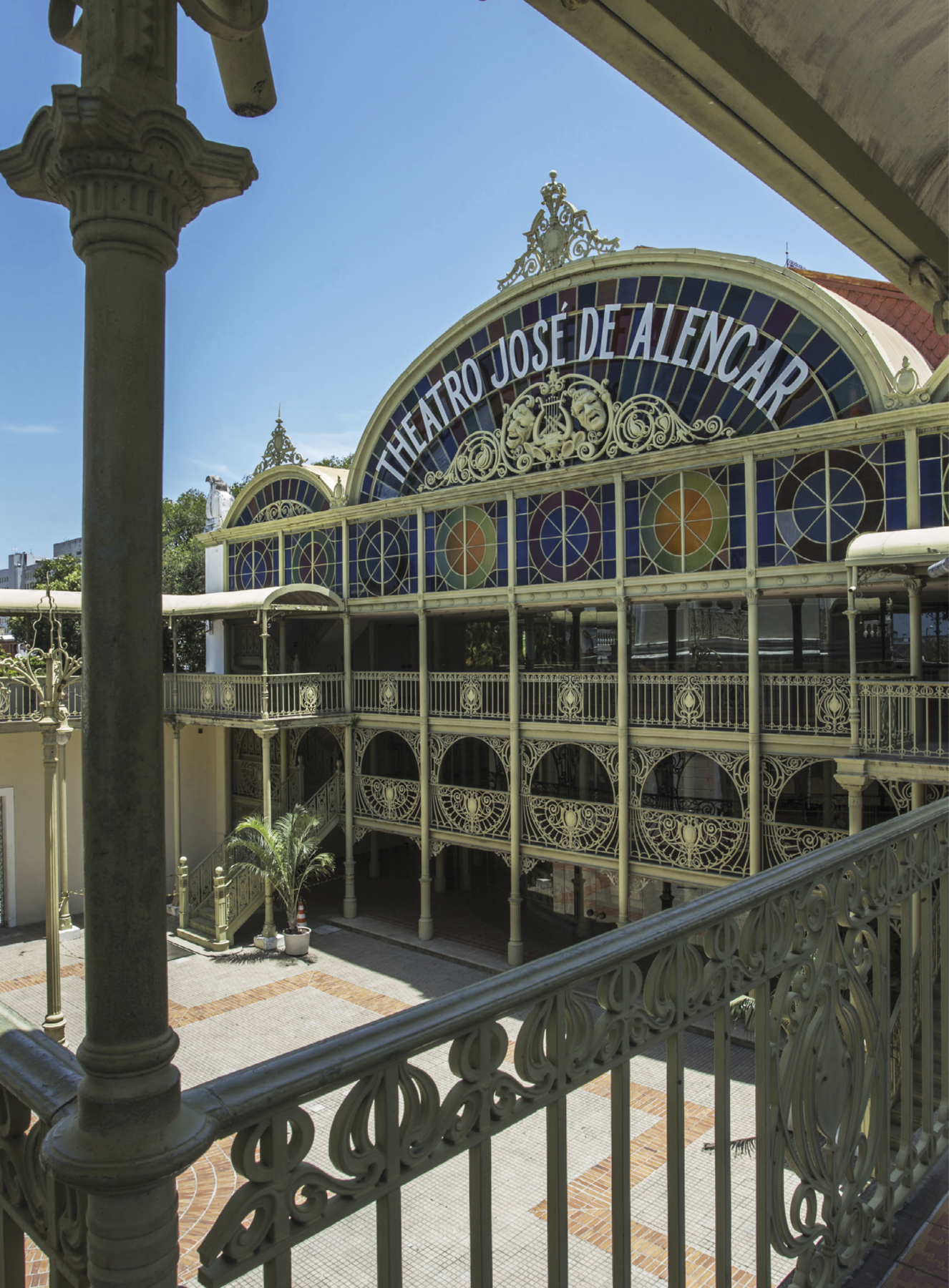 Fotografia. De uma sacada, vê-se uma grande construção com a informação na parte superior: Theatro José de Alencar, com arabescos enfeitando. O teto é arredondado, há sacadas e vidros coloridos, além de colunas.