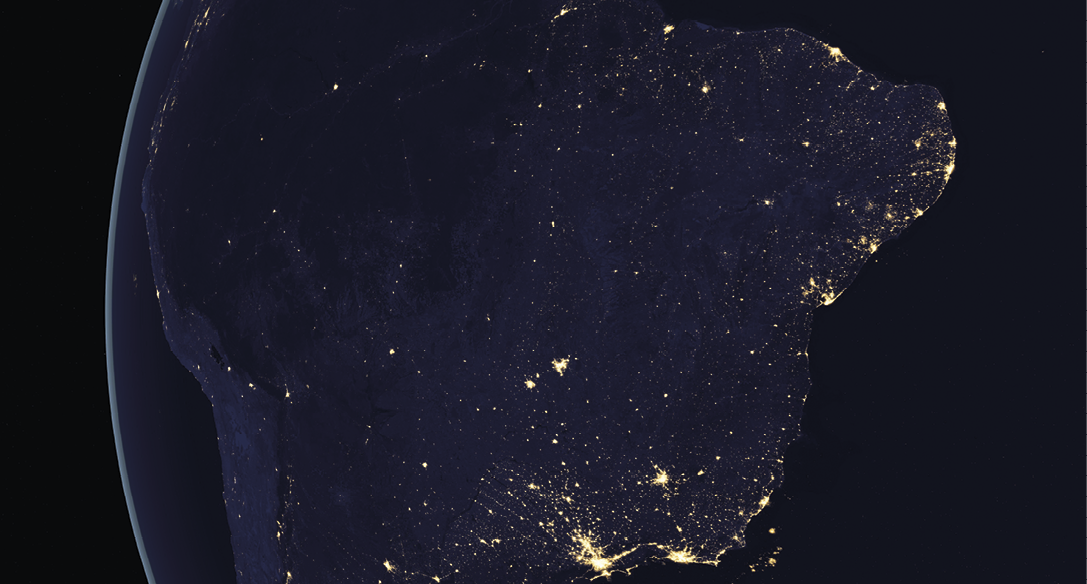 Imagem. Imagem de satélite de parte da América do Sul durante o período noturno. O continente está na cor azul escuro e nele aparecem pontos amarelos. Há concentração de pontos amarelos na costa brasileira da região Nordeste e da região Sudeste. O Oceano Atlântico, à direita, está na cor preta e o Oceano Pacífico aparece à esquerda.