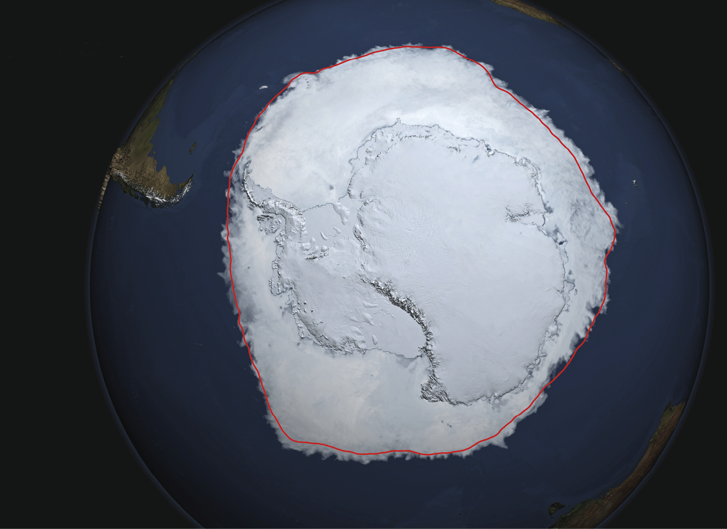 Imagem de satélite. 
Imagem de satélite com destaque para uma área  continental e marítima circundada por oceano, toda coberta de gelo. Uma linha vermelha circunda o essa área.