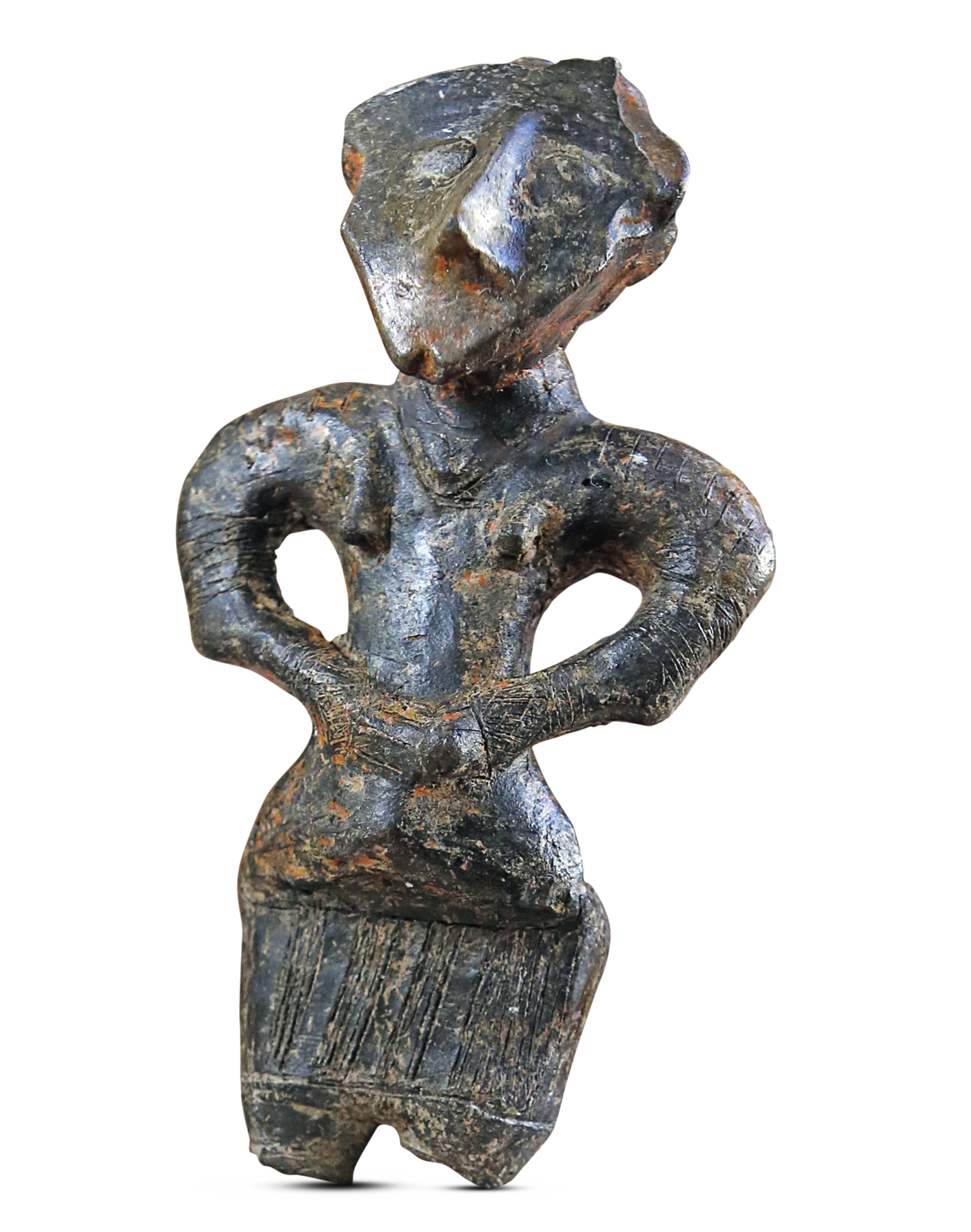 Fotografia. Em metal de cor escura com partes em marrom, uma estatueta vista de frente. Representa uma figura humana de nariz pontiagudo com as mãos sobre a cintura.