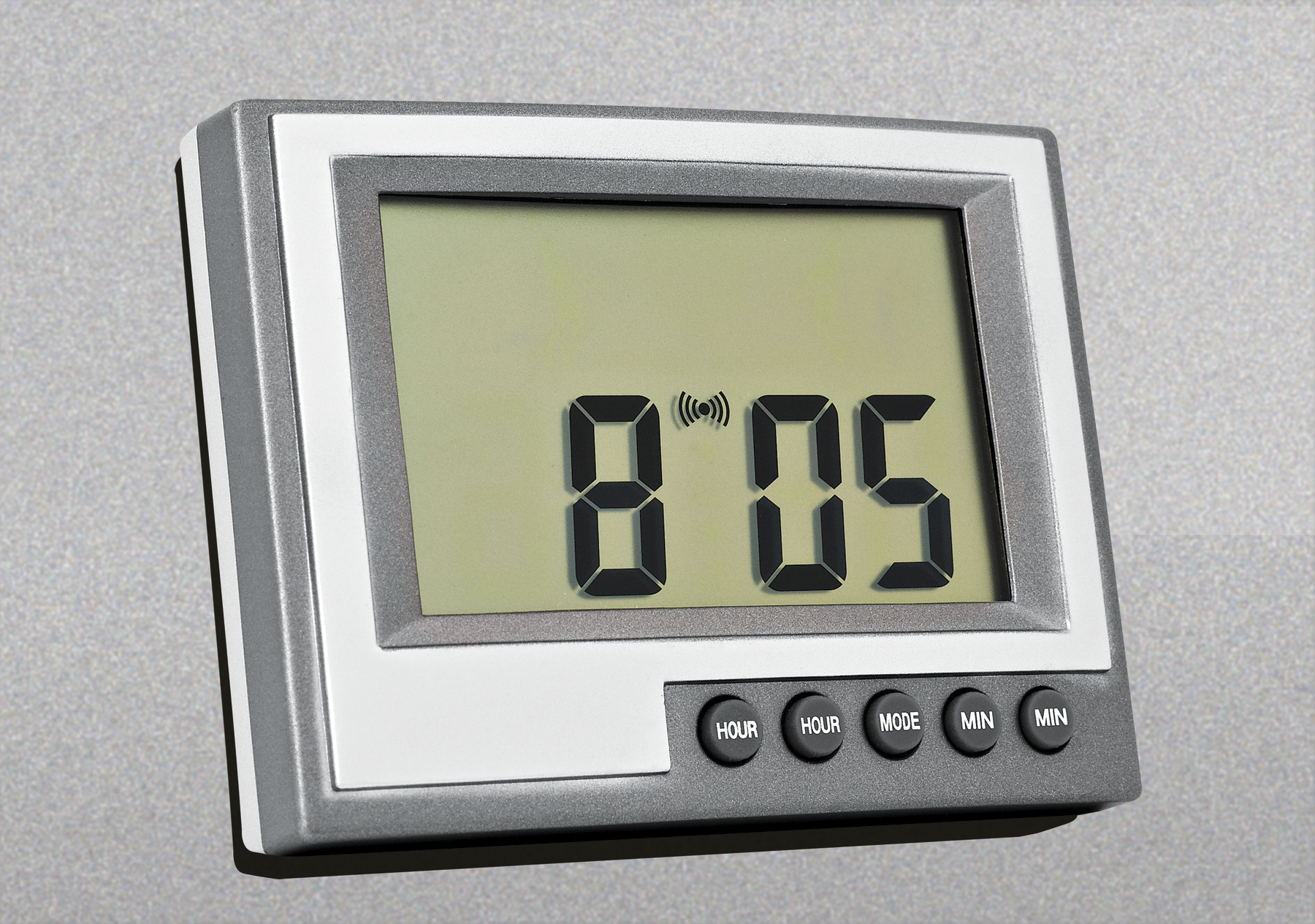 Fotografia. Um relógio digital horizontal de cor cinza, com botões na parte inferior. Na tela, a indicação do horário em números arábicos de cor preta: 8 horas e 5 minutos.