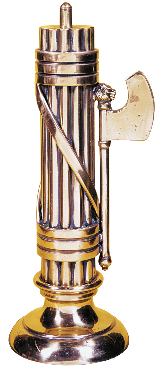 Escultura. Objeto dourado de forma cilíndrica, com a base inferior arredondada, com hastes finas verticais enfeixadas. À direita, atrelado ao feixe, um machado na vertical.