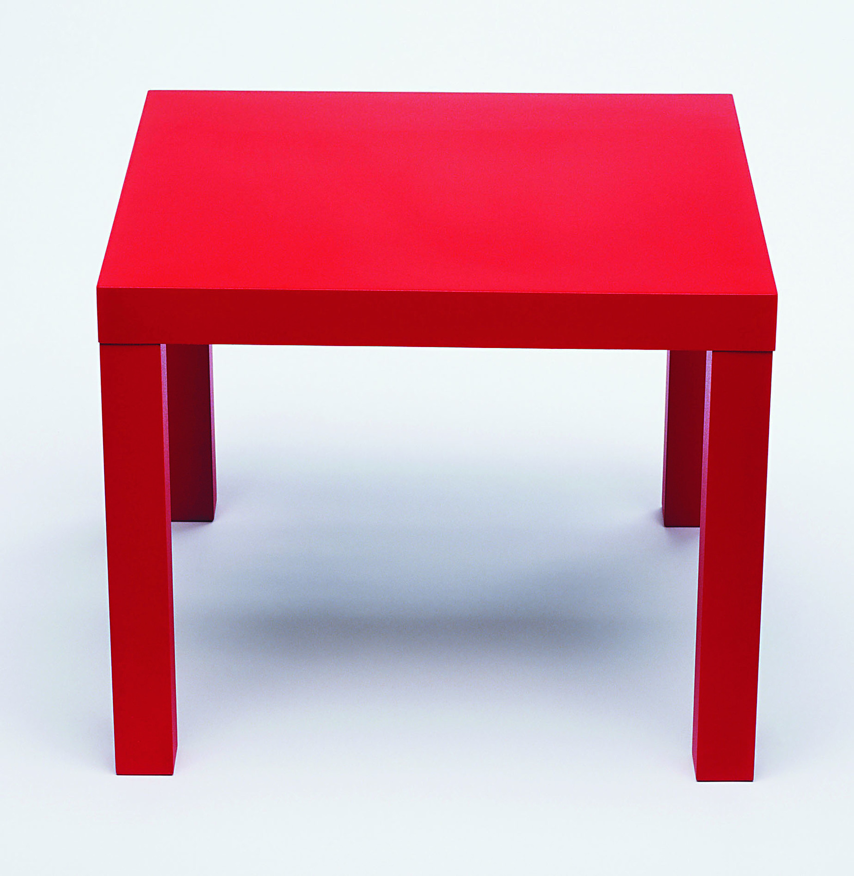 Fotografia. Mesa de tampo retangular para 4 pessoas. O tampo e os pés da mesa são vermelhos.