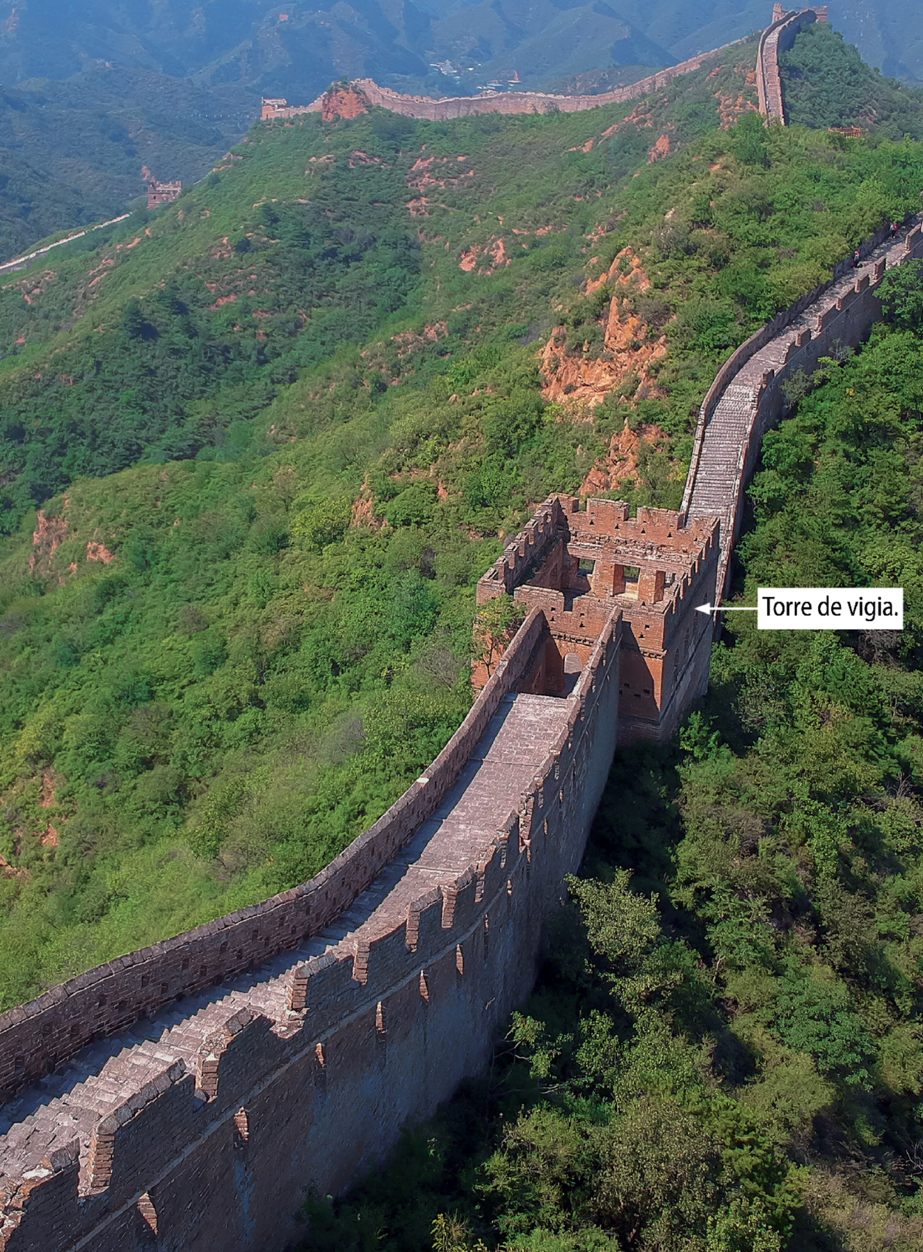 Fotografia. vista aérea parcial da Grande Muralha, China, em 2017. Com destaque para a torre de vigia, sem cobertura, feita de tijolos, com formato da base parecida com um quadrilátero.