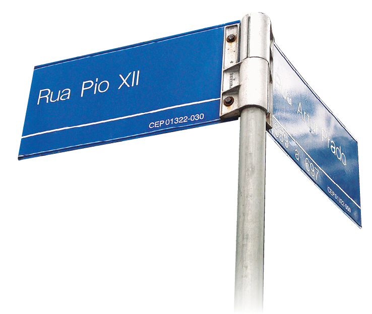 Fotografia. Uma placa de nome de rua. Rua Pio 12, sendo 12 representado no sistema de numeração romano.