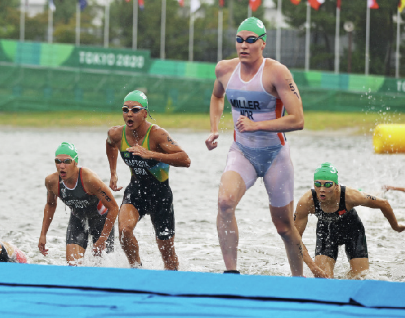 Fotografia. Atletas saindo da água, eles estão de macacão touca e óculos.