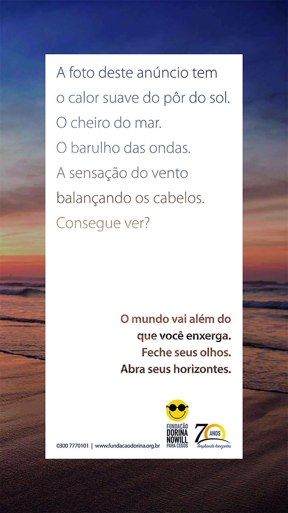 Cartaz. Sobre fundo branco, há um retângulo branco vertical com o seguinte texto: A foto deste anúncio tem o calor suave do pôr do sol. O cheiro do mar. O barulho das ondas. A sensação do vento balançando os cabelos. Consegue ver? O mundo vai além do que você enxerga. Feche seus olhos. Abra seus horizontes. 
Emoldurando o retângulo branco, há a vista parcial da fotografia de uma praia ao pôr do sol.