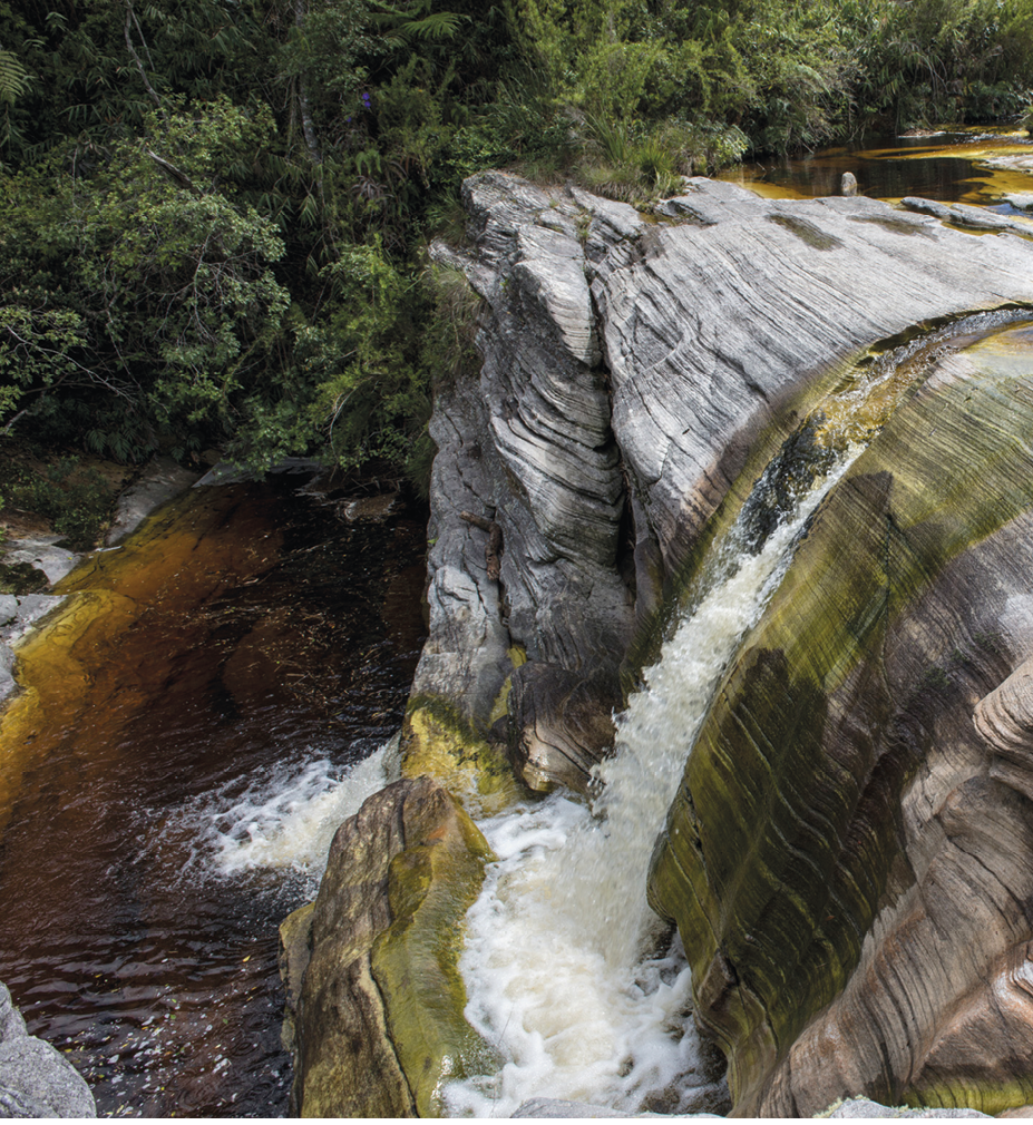 Fotografia. Paisagem natural com uma queda-d'água cercada de vegetação