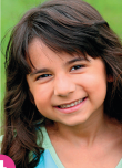 Imagem: Fotografia. Uma menina sorridente de longo cabelo castanho-escuro e liso. Fim da imagem.