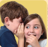 Imagem: Fotografia. Um menino está com as mãos ao lado da boca e fala no ouvido de uma menina que está atenta ao que escuta.  Fim da imagem.