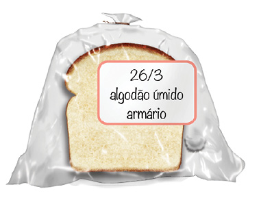 Imagem: Fotografia. Um saco plástico transparente com um pedaço de pão de forma de cor bege, com o contorno superior em marrom. Etiqueta com texto : 26/3 algodão úmido armário. Fim da imagem.