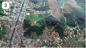 Imagem: Fotografia 3. Vista do mesmo local descrito anteriormente, com cidade à esquerda, a parte de vegetação e árvores menor e menos verde.  Fim da imagem.