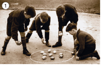 Imagem: Fotografia 1. Em tons de sépia. Quatro meninos jogando em rua. Ao centro, linha branca, com pequenas pedras arredondadas. Todos usam blusa de mangas compridas com bermuda e meias grandes, com sapatos escuros. Eles têm pele clara, cabelos escuros e cada um segura uma pedra na mão. Três deles estão em pé com o corpo agachado e à direita, menino agachado de joelhos no chão. Fim da imagem.