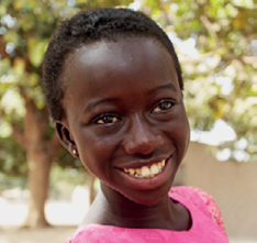 Imagem: Fotografia. Uma menina negra com cabelo curto está sorrindo. Fim da imagem.