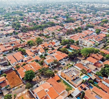 Imagem: Fotografia. Vista aérea de várias casas com árvores entre elas. Fim da imagem.