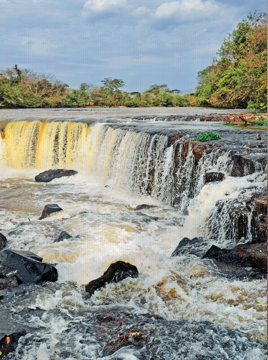 Imagem: Fotografia 1. Uma queda d’água com pedras em volta. Ao fundo, árvores.  Fim da imagem.