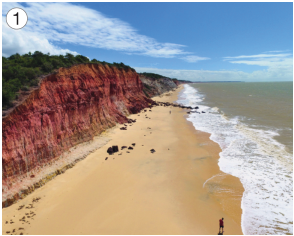 Imagem: Fotografia 1. À direita, orla da praia e à esquerda, montanhas. Fim da imagem.