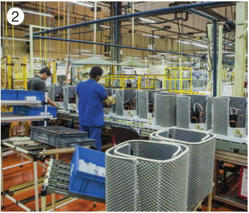 Imagem: Fotografia 2. Pessoas com uniforme azul estão com as mãos sobre aparelhos eletrônicos. Em volta há cabos e estruturas de metal. Fim da imagem.