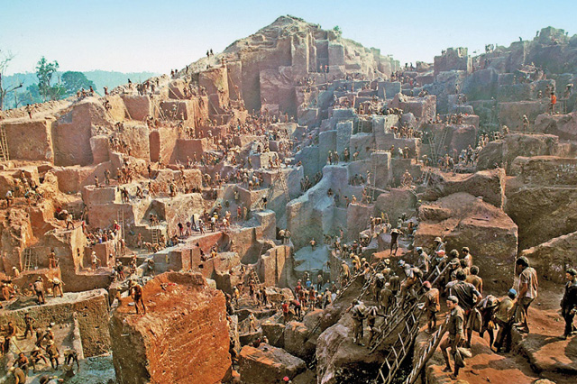 Imagem: Fotografia. Uma multidão espalhada em morros de pedra marrom. Fim da imagem.