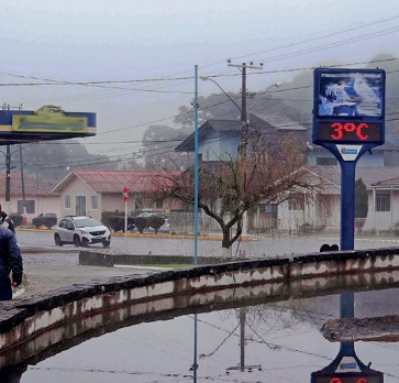 Imagem: Fotografia. Um termômetro indicando 3 ºC na rua. Ao fundo, carros, árvores e casas. Fim da imagem.