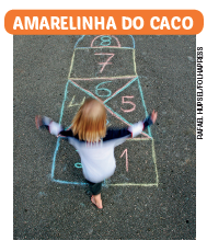 Imagem: Fotografia. Vista superior de uma menina de cabelo longo loiro, vestindo camiseta branca e calça azul, pulando em uma amarelinha do caco quadrada com divisões de números. 1 e 2, lado a lado, quadrado formado por 4 espaços em triângulos indicando 3, 4, 5 e 6. Finalizando com sequencia de dois quadrados 7 e 8.  Fim da imagem.