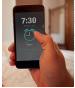 Imagem: Fotografia. Destaque de um dedo sobre celular apresentando um alarme com horário marcado “7:30”. Fim da imagem.