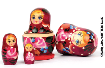 Imagem: Fotografia 2. Boneca russa rosa com rosto de uma menina loira e olhos azuis. Há quatro bonecas de tamanhos diversos. Fim da imagem.