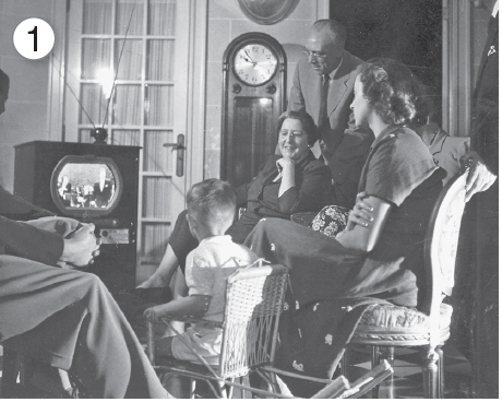 Imagem: 1. Fotografia em preto e branco. Família sentada em cadeiras e poltronas próximas a frente de uma televisão retangular e larga de madeira com tela pequena arredondada. Fim da imagem.