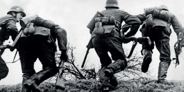 Imagem: Fotografia em preto e branco. Homens de capacete e farda, segurando armas, subindo um morro de grama. Fim da imagem.