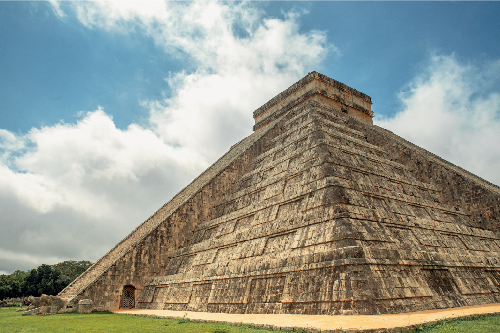 Imagem: Fotografia: templo em pirâmide de quatro lados, nos centros de quatro lado há escadas e topo reto.  Fim da imagem.
