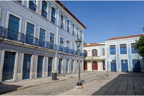 Imagem: Fotografia. Faixada de casa de três andares azul com varanda estreita e portas pequenas azuis.    Fim da imagem.