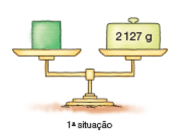 Imagem: Ilustração. 1ª situação: balança de pratos. No prato à esquerda, um cubo verde. No prato à direita, um peso com 2.127 g.   Fim da imagem.