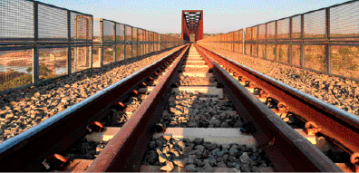 Imagem: Fotografia. Trilhos de trem com pedras em volta.  Fim da imagem.