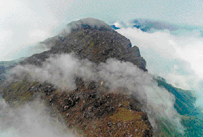 Imagem: Fotografia. Pico coberto de neblina.   Fim da imagem.