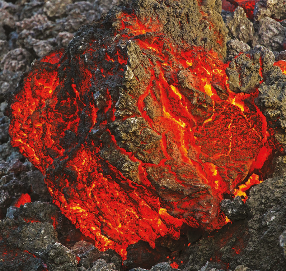 Fotografia. Destaque para um pedaço de lava com partes vermelhas e partes cinzas.