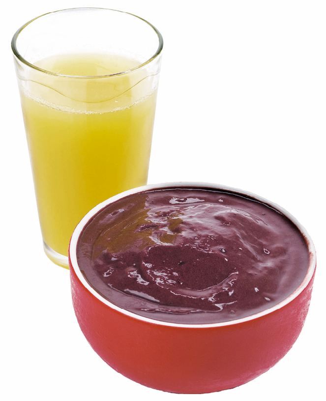 Fotografia. Um copo de vidro com líquido amarelo e uma cumbuca laranja com um creme roxo dentro.