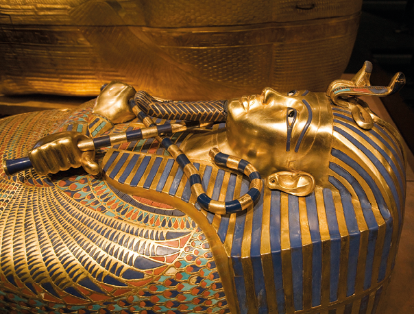 Fotografia. Tumba com o rosto de um faraó em dourado e preto.