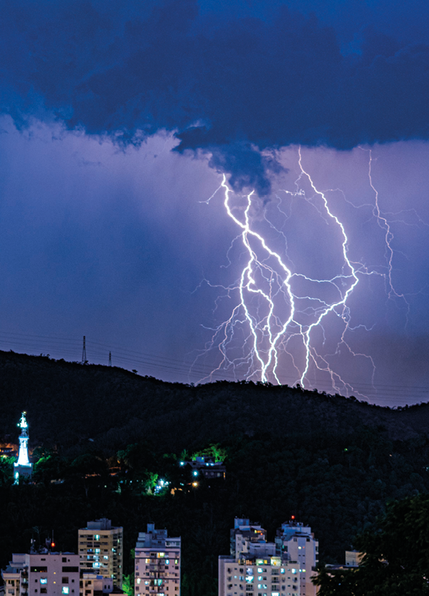 Fotografia. Relâmpagos saindo de uma nuvem escura no céu noturno.