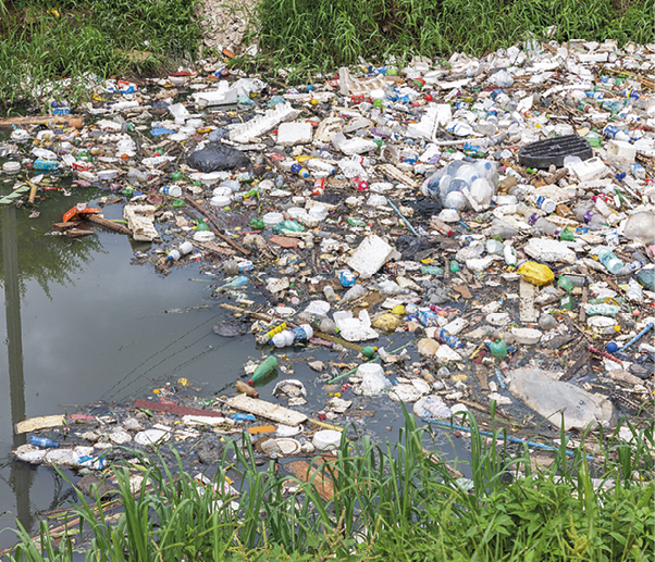 Fotografia. Resíduos sólidos acumulados no leito de um rio.