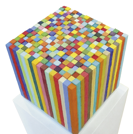 Fotografia. Escultura que tem o formato de um cubo, feita por meio da junção de barras coloridas que tem formato de bloco retangular.