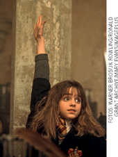 IMAGEM: hermione está em aula e levanta uma das mãos para fazer uma pergunta. FIM DA IMAGEM.