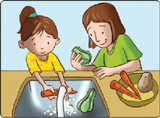 IMAGEM: uma menina e uma mulher lavam os legumes na pia e os colocam em um recipiente. FIM DA IMAGEM.