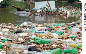 IMAGEM: lixo acumulado nas margens de um rio. há muitas garrafas plásticas, restos de embalagens e outros resíduos. FIM DA IMAGEM.
