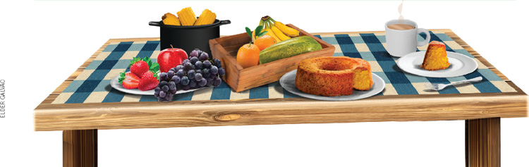 IMAGEM: sobre uma mesa, há um prato com morangos, uvas e maçã, uma panela com espigas de milho, uma bandeja com laranjas, bananas e mamão, um prato com um bolo, uma xícara com uma bebida quente e uma fatia do bolo em um prato de sobremesa, atrás de um garfo. FIM DA IMAGEM.