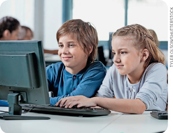 IMAGEM: um menino e uma menina estão sentados lado a lado em frente a um computador. FIM DA IMAGEM.